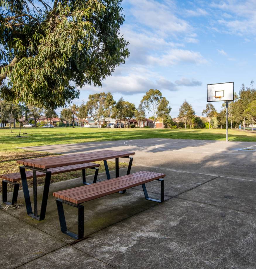 Public park with picnic tables, benches, and a basketball hoop in a suburban neighborhood of Melbourne, Australia. Concept of outdoor recreation, community facilities, and family-friendly spaces.